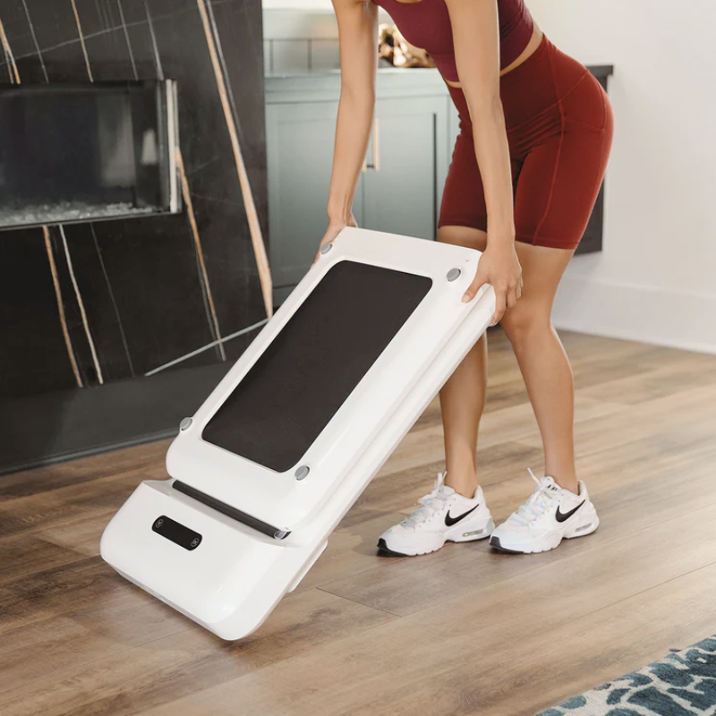 Woman folding away the WalkingPad C2 Treadmill in White colour inside a home lounge