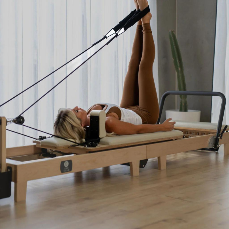 Woman exercising on the Core Collab Eco Foldable Pilates Reformer Machine