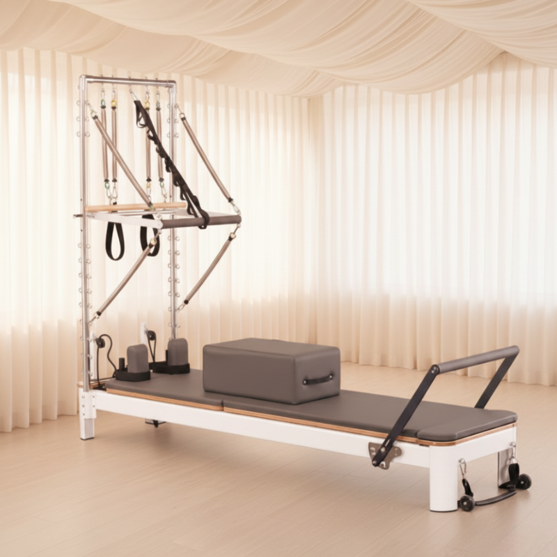 Core Collab Queen Reformer with Half Trapeze in a Pilates studio with soft lighting and curtain drapes.