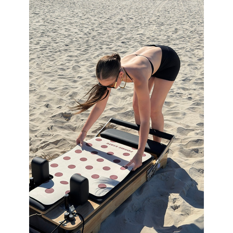 Woman adjusting Forme State Pilates Mat for Reformer in Butter at the beach