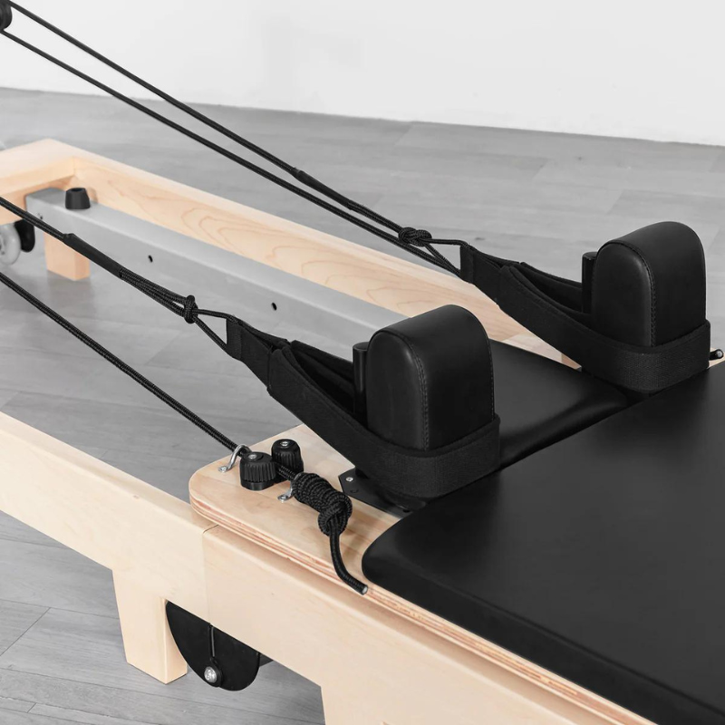 Close-up of the ropes and straps and the shoulder rests on the Contour folding wooden pilates reformer machine in Black