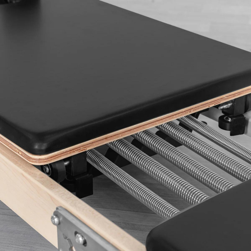 Close-up of the carriage and springs on the contour folding wooden pilates reformer machine in Black