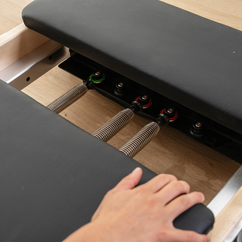 Close-up of a few springs hooked on the Contour folding wooden pilates reformer machine in Black colour