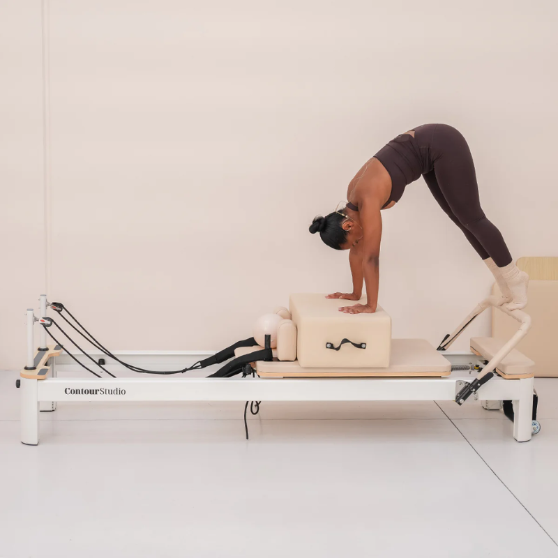 Woman exercising with Pilates box and Lifespan Fitness Contour Studio Commercial Reformer Pilates Machine inside a studio