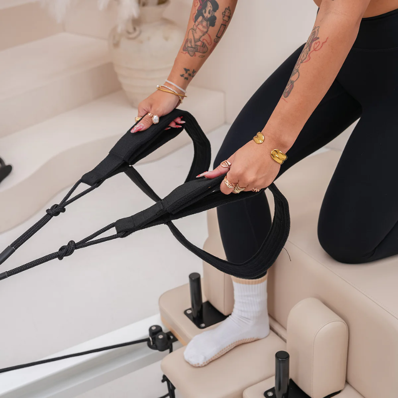 Woman holding the double-loop handles on the Lifespan Fitness Contour Studio Commercial Pilates Reformer Machine in Beige