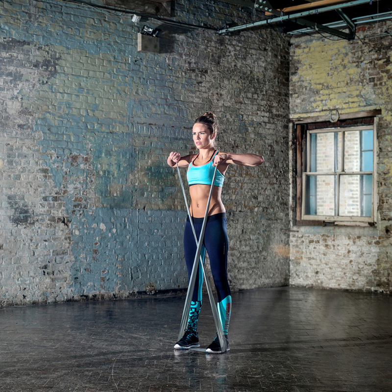 Woman working out inside a studio with the grey Reebok Resistance Band