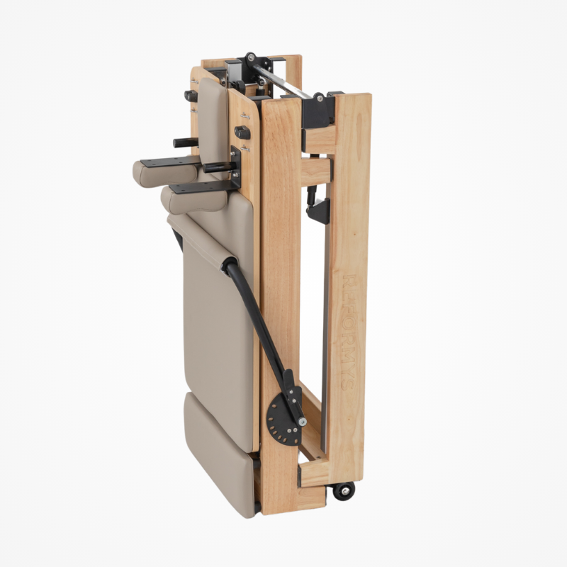 Side angled view of Reformys Cloud Foldable Pilates Reformer in Beige in folded position