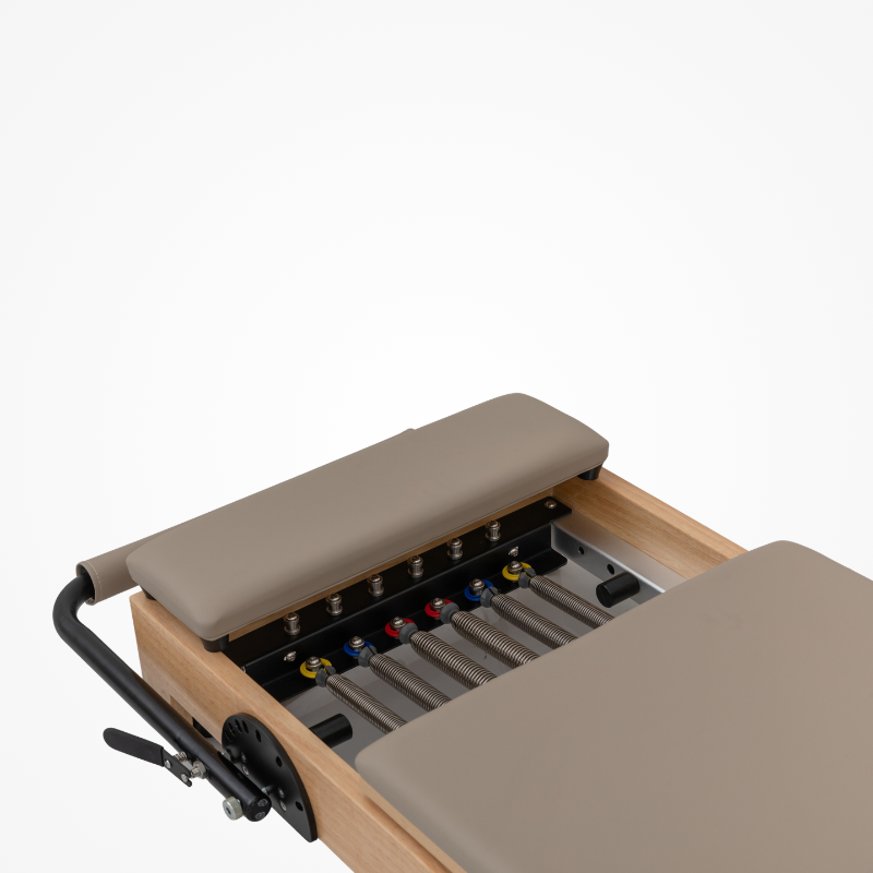 Close-up of padded standing platform, springs, and carriage bed of Reformys Cloud Foldable Pilates Reformer in Beige
