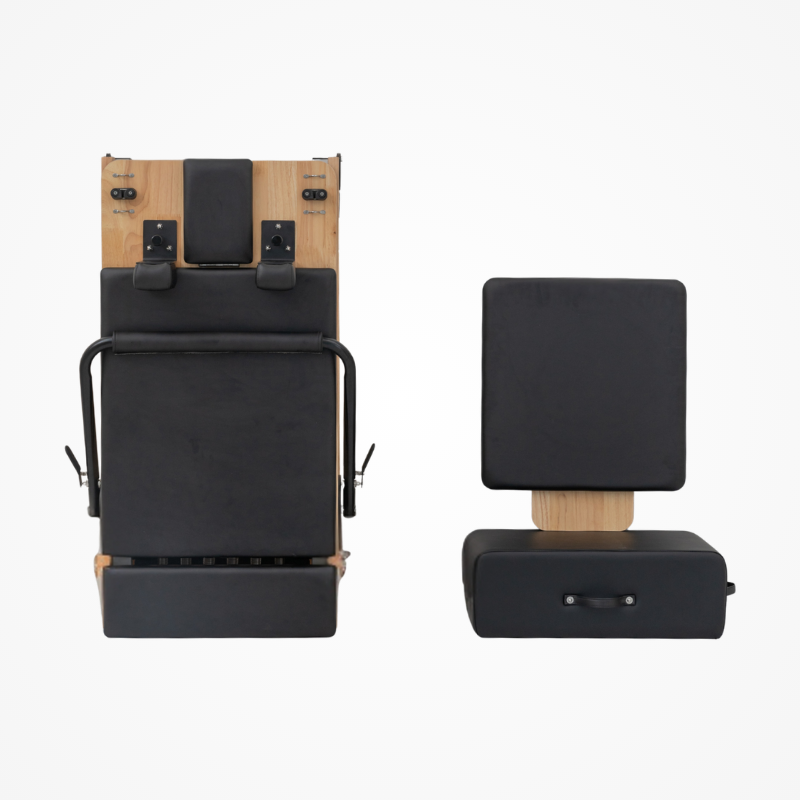 Front view of Reformys Cloud Folding Pilates Reformer in Black in folded position with jumpboard and Pilates box next to it