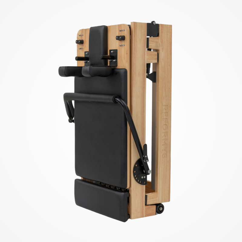 Side angled view of the Reformys Cloud Foldable Pilates Reformer in Black in folded position