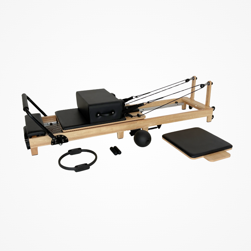 Left front angled view of the Reformys Cloud Foldable Pilates Reformer in Black with accessories and jumpboard next to it