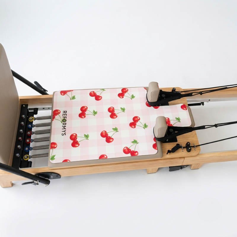 Reformys Pilates Reformer Mat in Cherry Crush on a Pilates reformer machine with white background