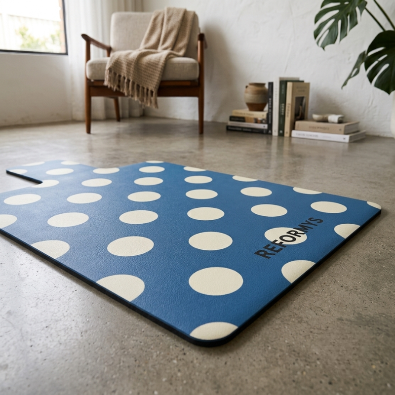 Reformys Pilates Reformer Mat in Ocean Dot laid on the floor of a home lounge