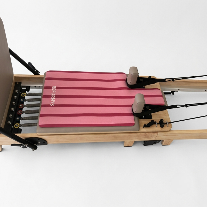 Reformys Pilates Reformer Mat in Sweet Rebel on a Pilates reformer machine with white background