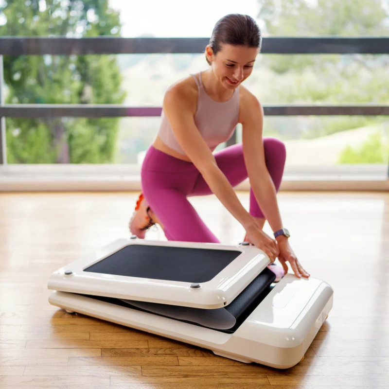 Woman folding up the WalkingPad C2 Compact Folding Treadmill in White