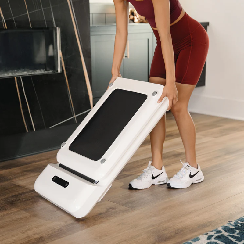 Woman storing away the WalkingPad C2 Compact Folding Treadmill in White