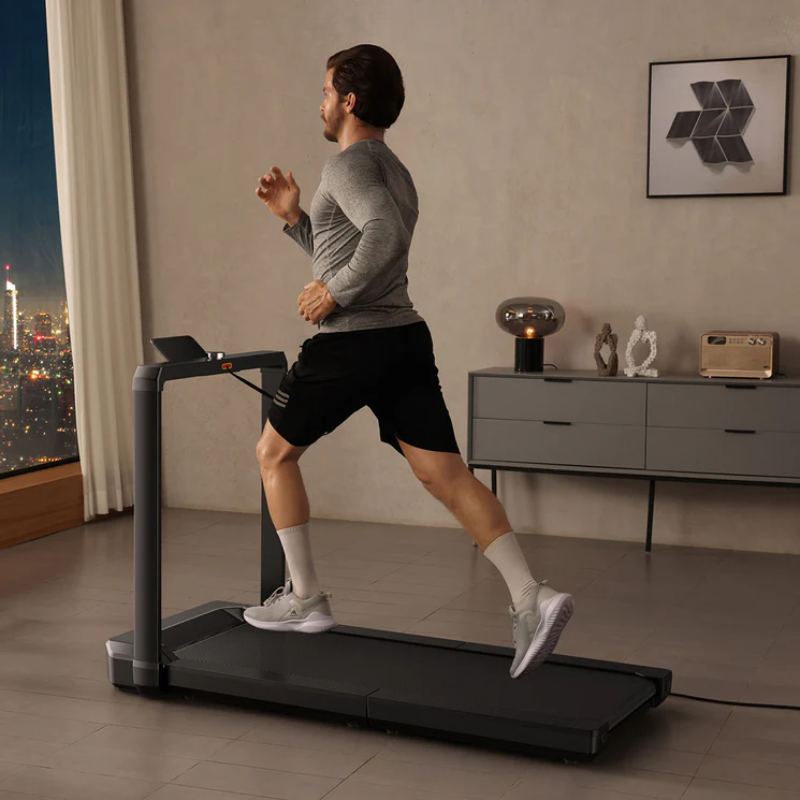 Man running on the WalkingPad MX16 Folding Treadmill in a modern living room with cityscape view.