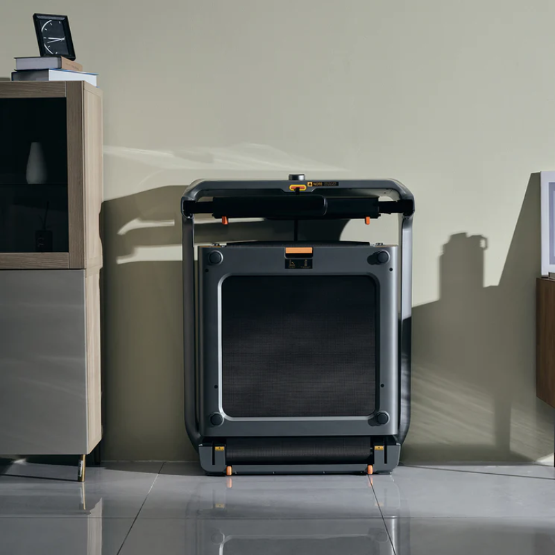WalkingPad X218 Foldable Treadmill stowed against a wall in a living room