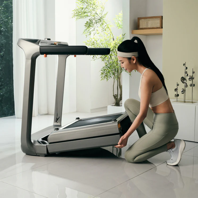 Woman kneeling and unfolding the WalkingPad X218 Double-Fold Treadmill
