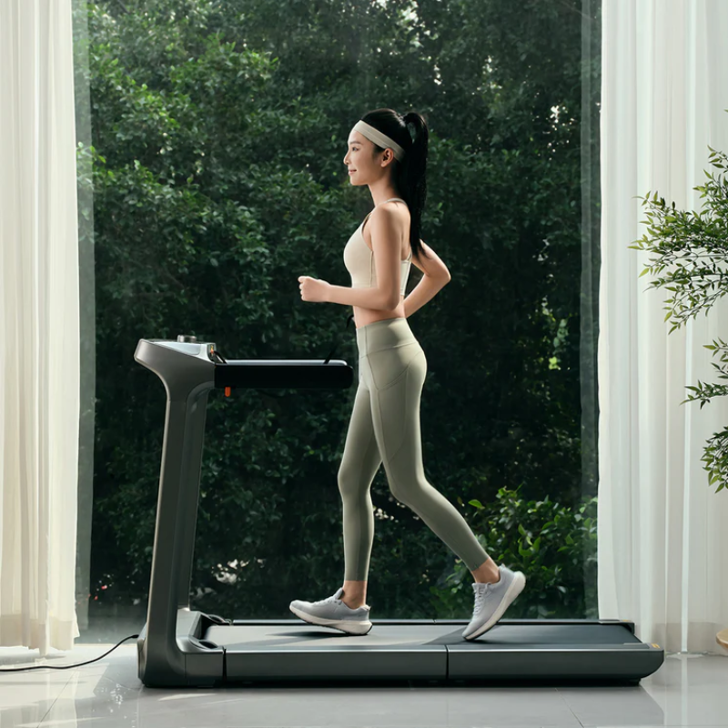 Woman running on the WalkingPad X218 Foldable Treadmill in a bright room with large window and greenery outside