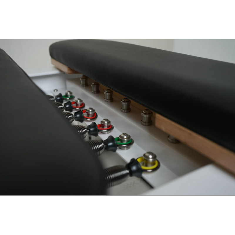 Close-up of the springs and spring platform on Core Collab Full Track Queen Studio Pilates Reformer Machine in White Frame and Black Upholstery