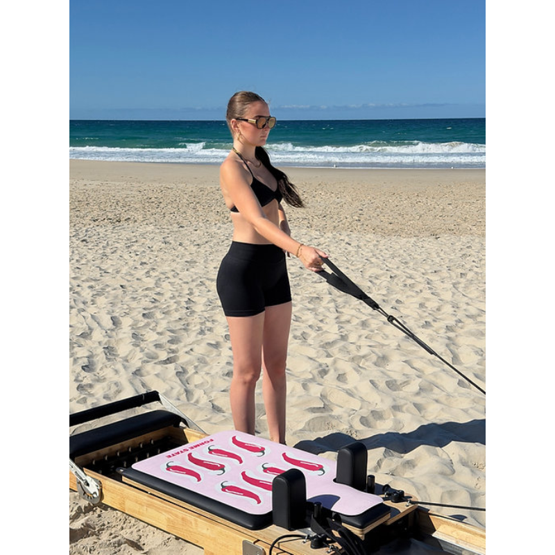 Woman exercising with Forme State Pilates Mat for Reformer in Chilli at the beach