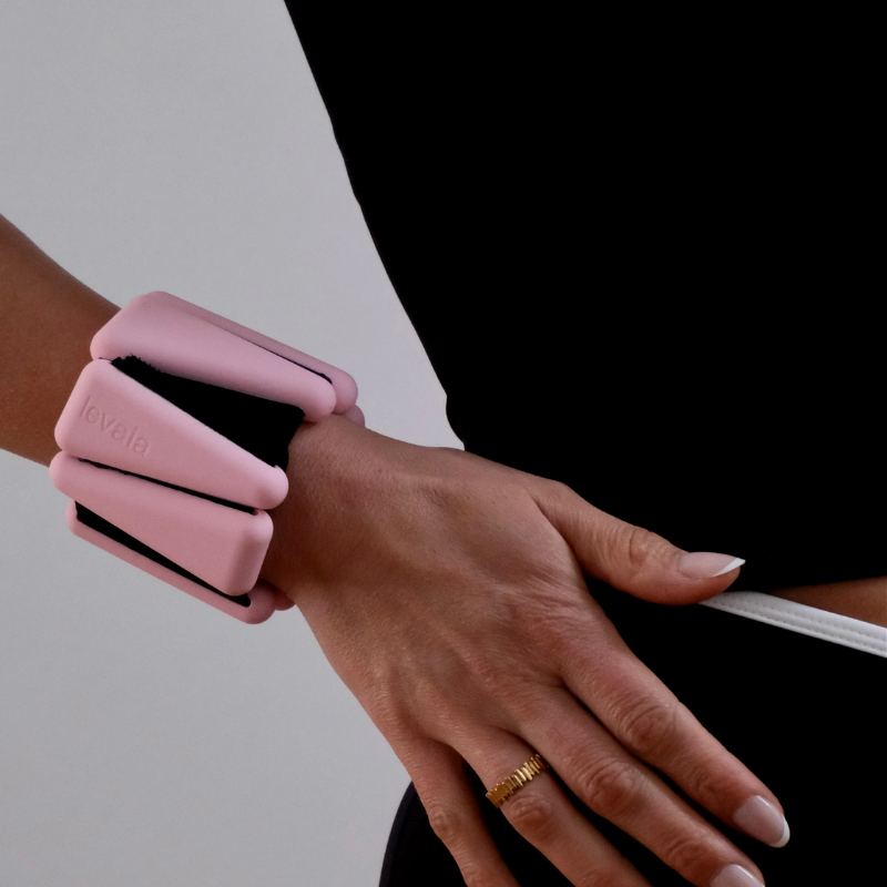 close-up of woman wearing levaïa wrist weights in classic blush on her wrist
