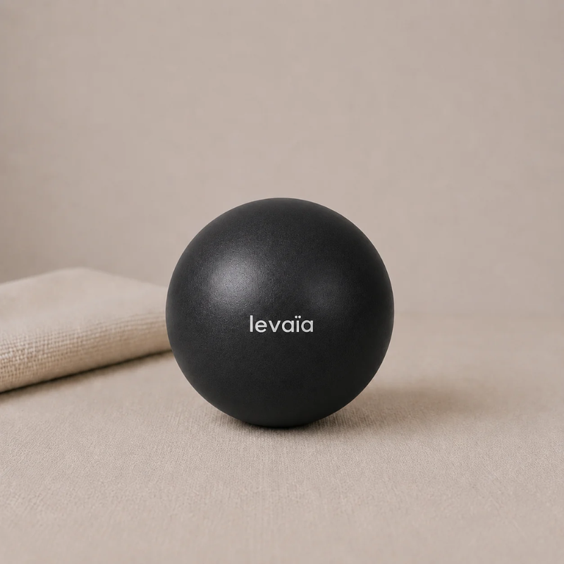levaïa luna Soft Pilates Ball in Noir, resting on a beige surface beside a folded towel.