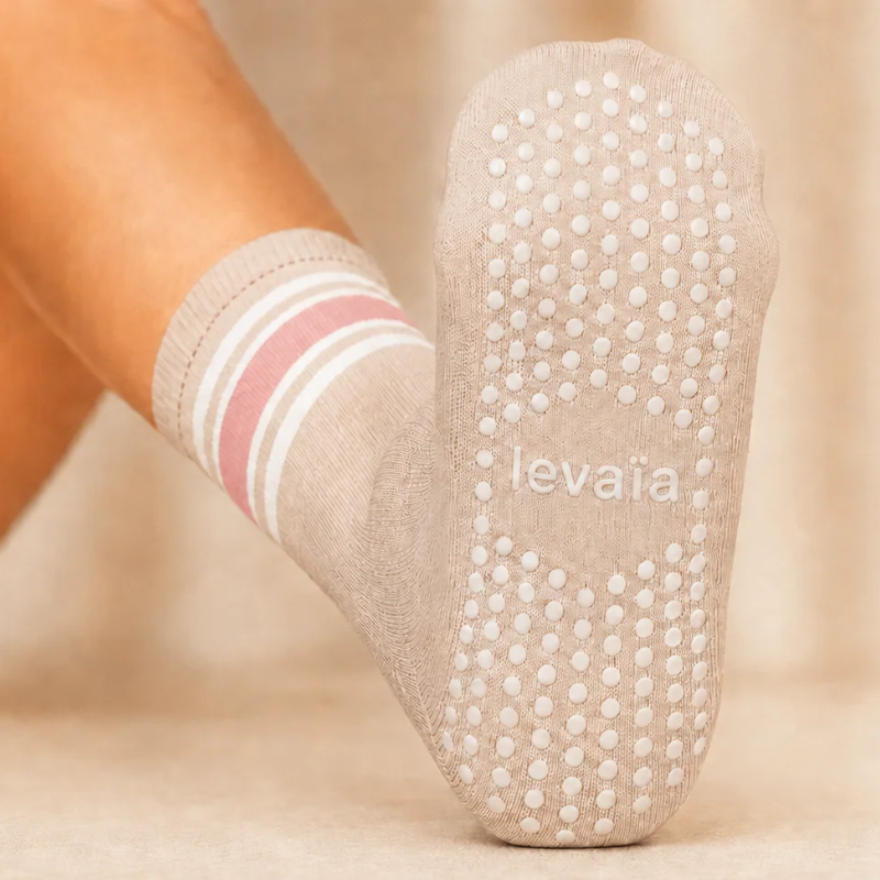 Sole of a levaïa Pilates Grip Sock in Blush, showing white grip dots and the levaïa logo, with pink and white ankle stripes.
