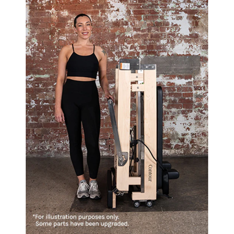 A woman standing next to a folded Lifespan Fitness Contour Folding Wooden Pilates Reformer Machine