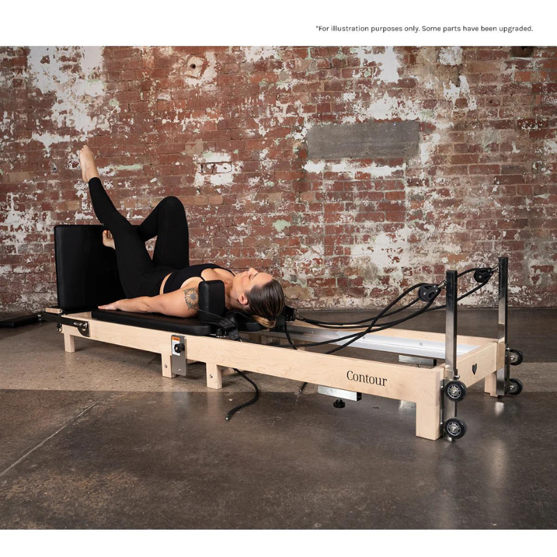 Full view of a woman exercising on her back on the Lifespan Fitness Contour Folding Wooden Pilates Reformer Machine in Black