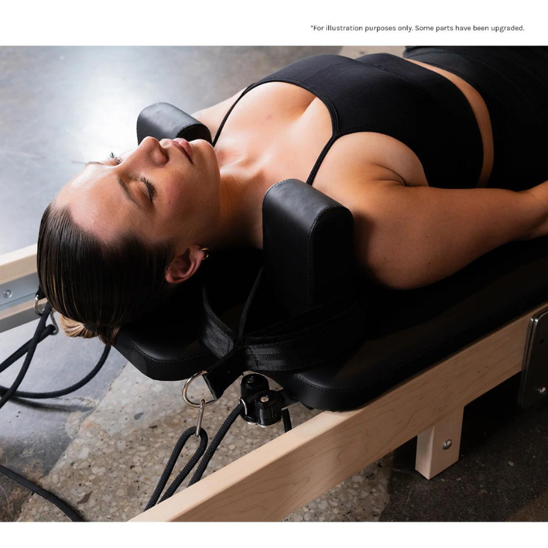 Close-up of a woman exercising on her back on the Lifespan Fitness Contour Folding Wooden Pilates Reformer Machine in Black