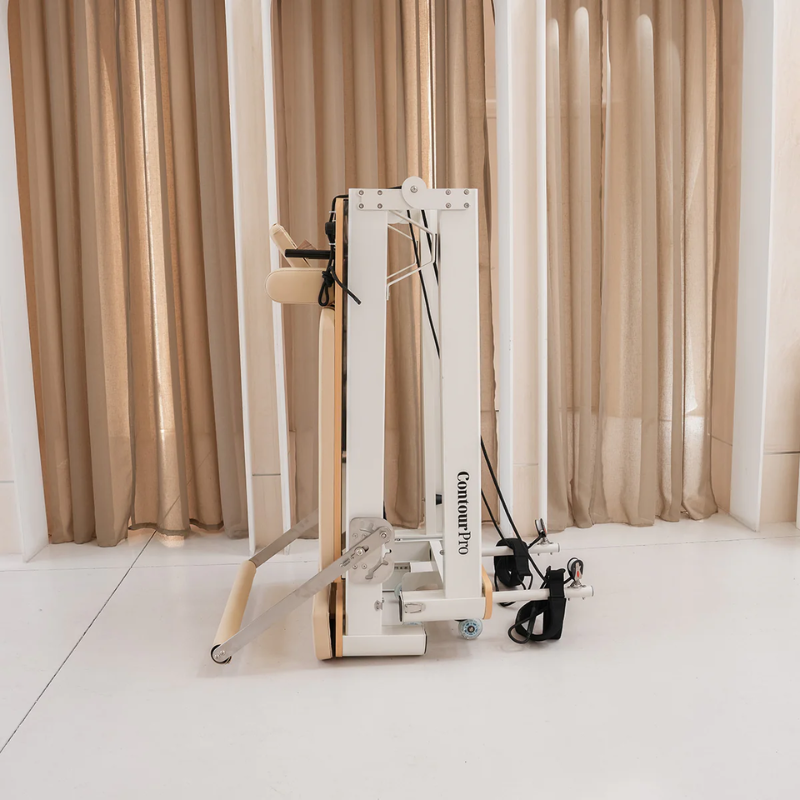 Side view of the Lifespan Fitness Contour Pro Aluminium Folding Reformer Pilates Machine in Beige in folded upright position inside a minimalist studio