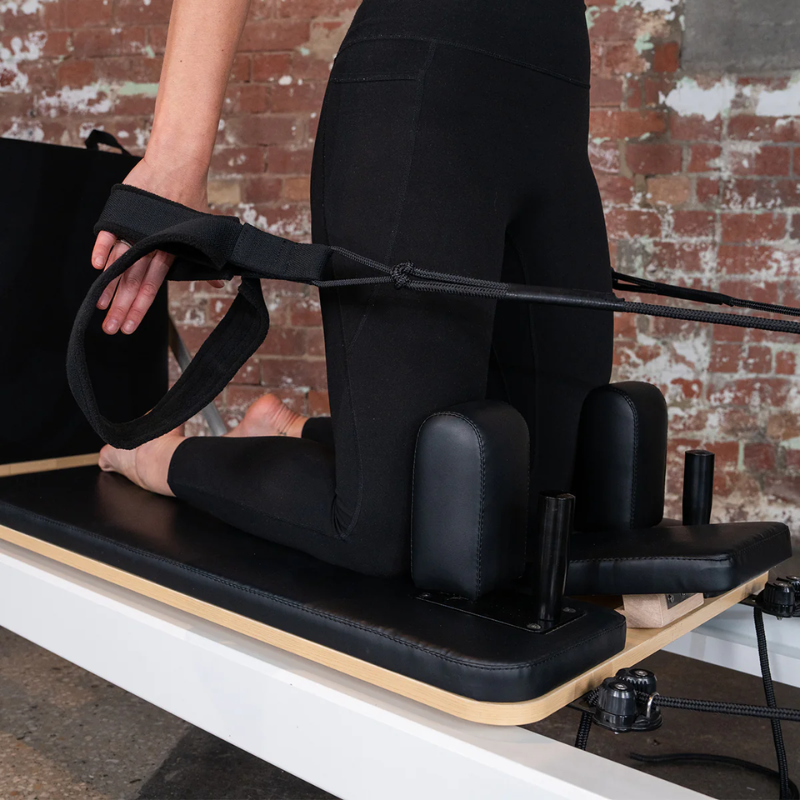 Close-up of a woman on the carriage of the Lifespan Fitness Contour Pro Aluminium Pilates Reformer Machine in Black