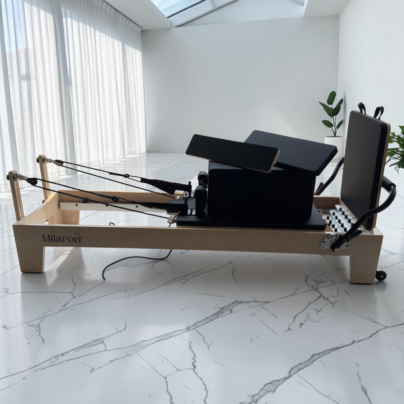 Milaron Maple V3 Studio Reformer with both padded and grip standing platforms sitting on the Pilates box