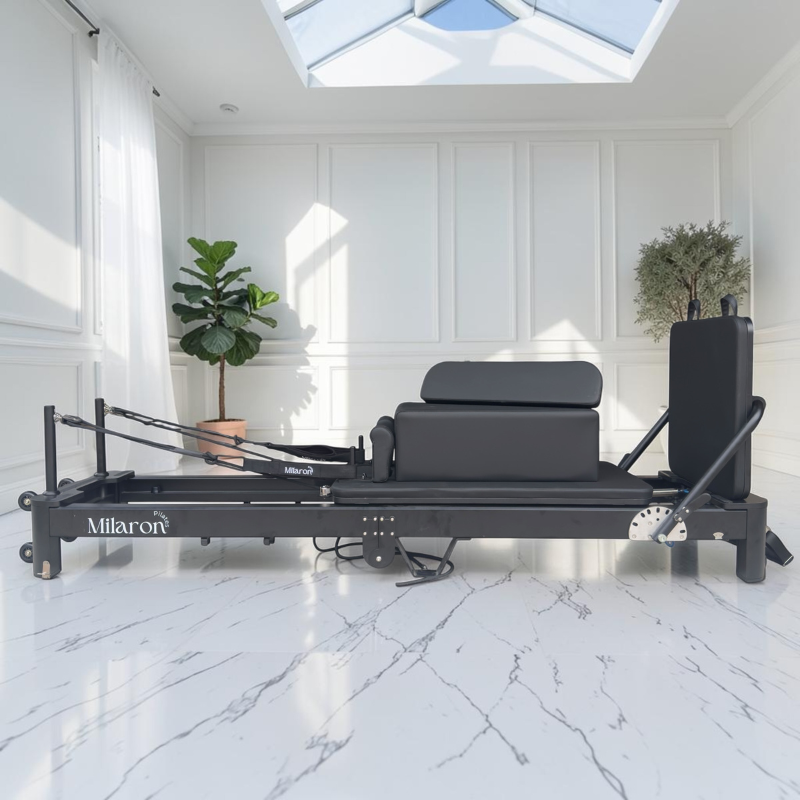 Side view of Milaron Pearl V3 Foldable Pilates Reformer in Noir with padded standing platform sitting on Pilates box