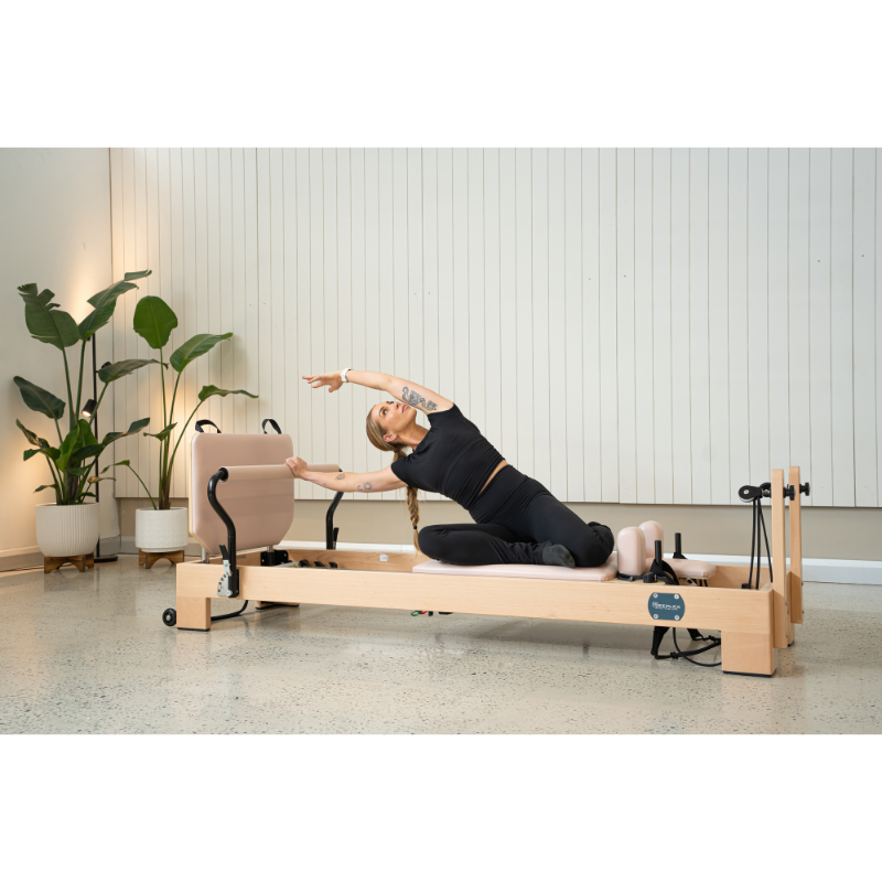 Woman doing the mermaid stretch on the Reeplex Luna Beechwood Pilates Reformer Machine.