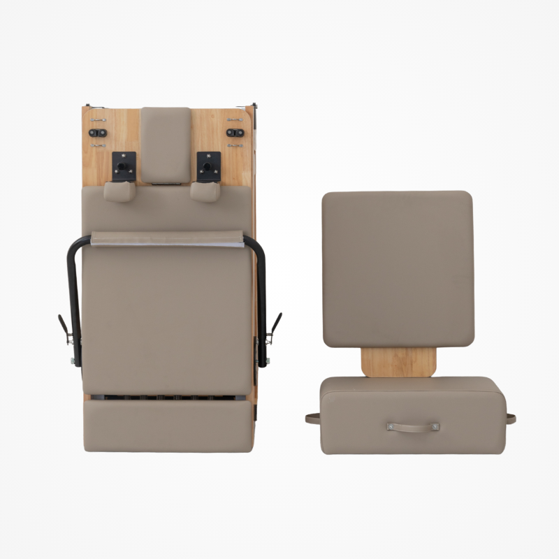 Front view of the Reformys Cloud Folding Pilates Reformer in Beige in folded position with jumpboard and Pilates box next to it