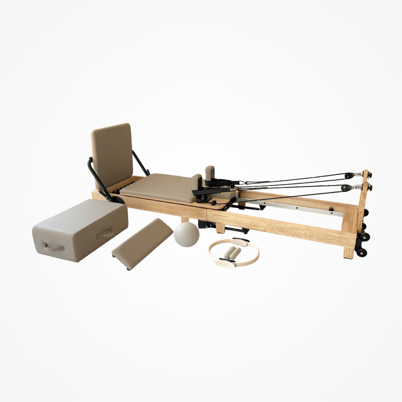 Angled left side back view of the Reformys Cloud Folding Pilates Reformer in Beige with all Pilates accessories next to it