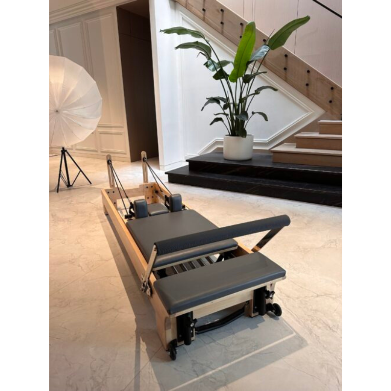 Volt Q2 Maple Wood Studio Pilates Reformer in a luxury home by stairs and large potted plant