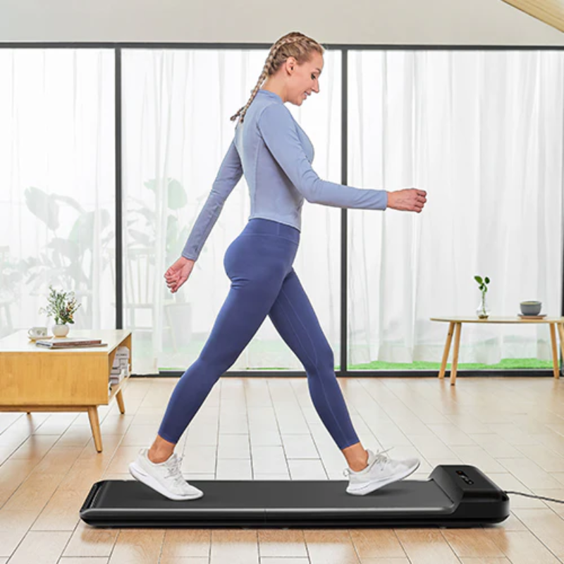 A woman walking on the WalkingPad C2 Compact Folding Treadmill in her lounge