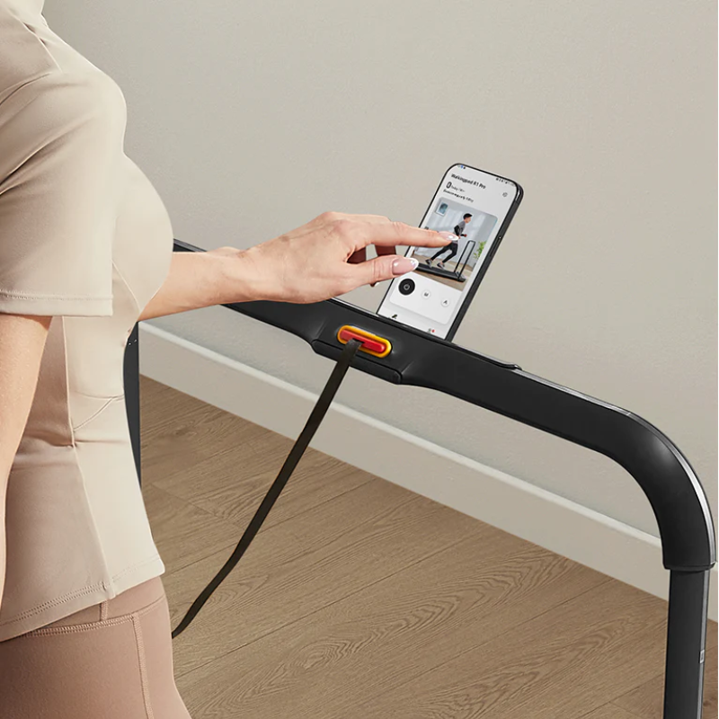 Zoomed in view of a woman using her mobile phone while walking on the Kingsmith WalkingPad Treadmill R1​